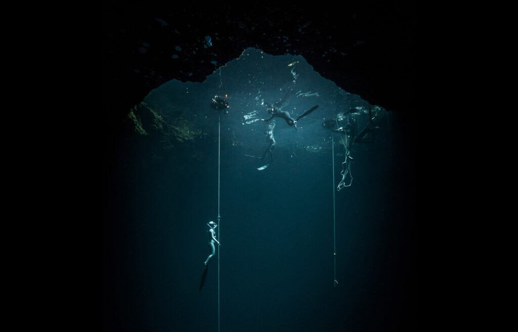 Freediver performing an AIDA 3 freediving descent along a line in deep blue water with pranamaya freediving