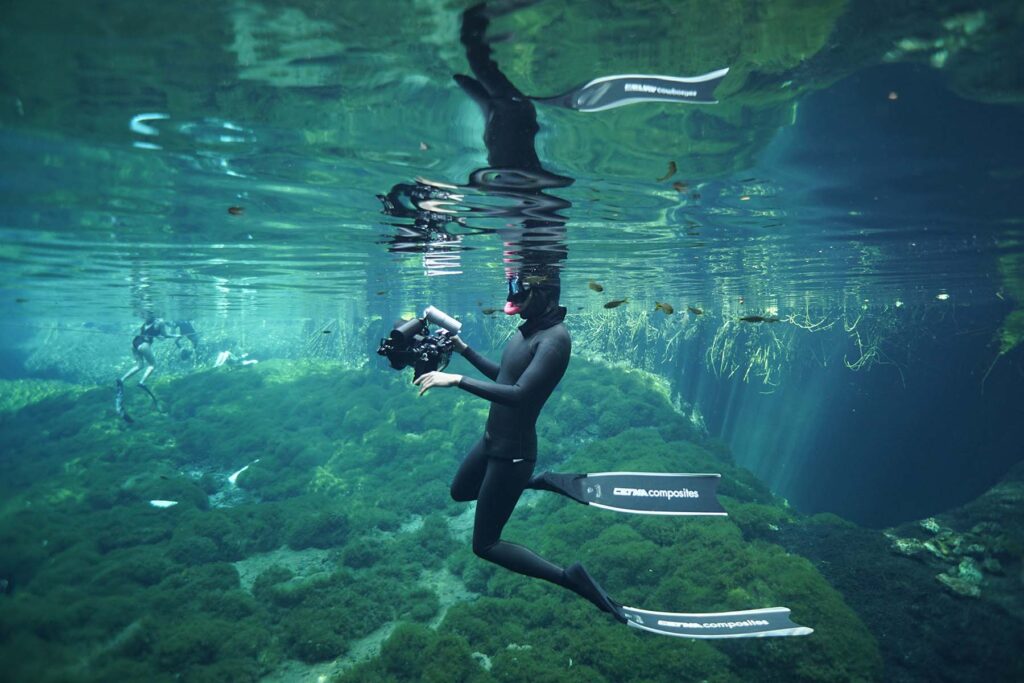 Freediver filming underwater scenes in a cenote in the Riviera Maya